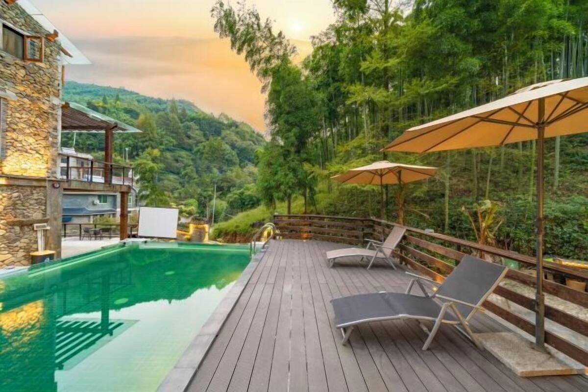 A wooden deck with a pool, lounge chairs, and umbrellas.