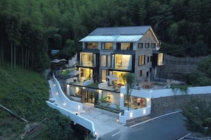 A modern two-story house with a flat roof, large windows, and a well-lit interior. - Heshi Mogan Hotel (Deqing)