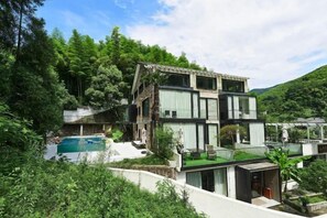 A modern two-story house with a swimming pool, surrounded by lush greenery and hills. - Heshi Mogan Hotel (Deqing)