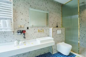 A bathroom with a white sink, a mirror, a toilet, and a shower area. - Heshi Mogan Hotel (Deqing)
