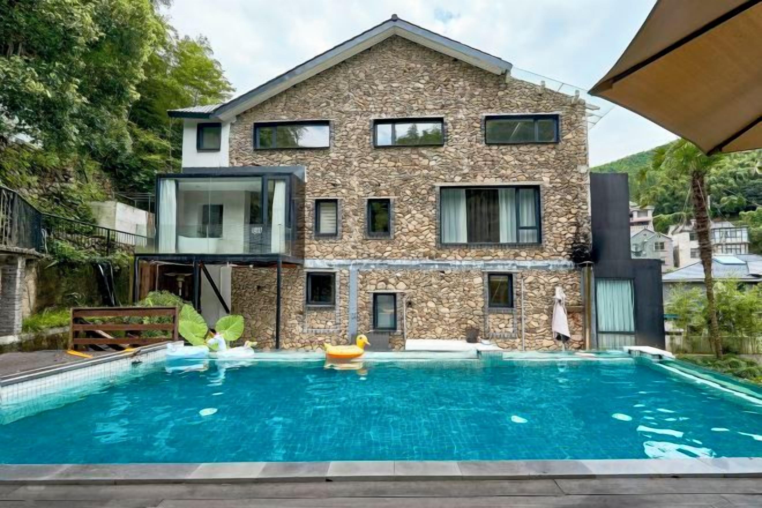 A modern two-story building with a swimming pool in front.
