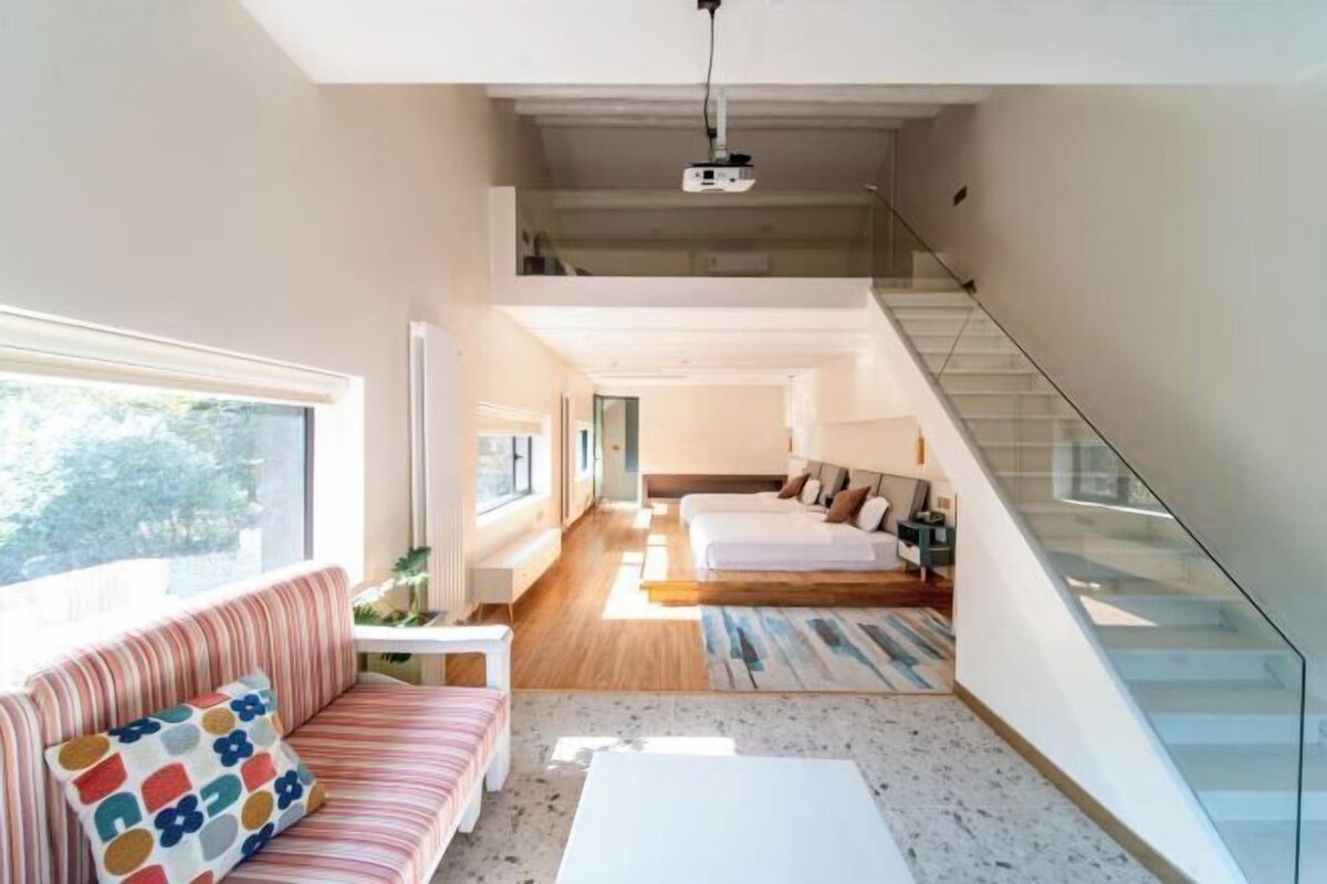 A modern interior with a sofa, a coffee table, a staircase, and a bed.