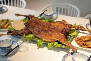A roasted duck on a table with plates of food and bowls. - Heshi Mogan Hotel (Deqing)