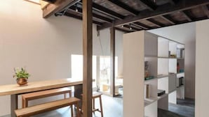 Une pièce comprenant un banc en bois, une petite table et une étagère blanche.