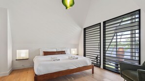 Un dormitorio moderno con una cama de madera, mesitas de noche y un ventanal con persianas.
