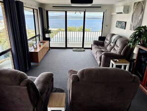 Ein Wohnzimmer mit einer Couch, einem Couchtisch und Meerblick durch große Fenster.