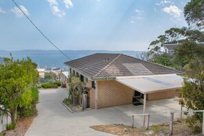 Ein zweistöckiges Gebäude mit Ziegeldach, einer Veranda und Blick auf das Meer.