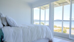 Ein Schlafzimmer mit großem Fenster, einem Bett und einem Nachttisch.