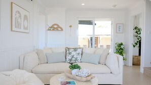 Ein geräumiges Wohnzimmer mit einem weißen Sofa, einem runden Couchtisch und Blick ins Freie.