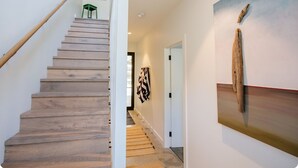 A wooden staircase leading to a room with a painting and a wooden sculpture. - Welcome to Whale Song (Middleton Beach)