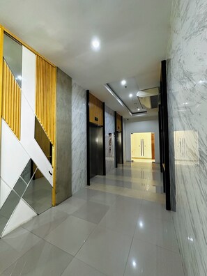 Stunning lobby with a central staircase, minimalist elevators, and sleek floor.