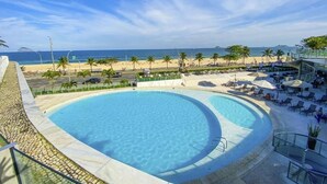 A pool with a view of the beach and palm trees. - Mais que um Hotel, uma Obra de Arte (São Conrado Rio de Janeiro)