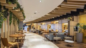A modern lounge area with wooden flooring, round tables, and comfortable seating. - Mais que um Hotel, uma Obra de Arte (São Conrado Rio de Janeiro)