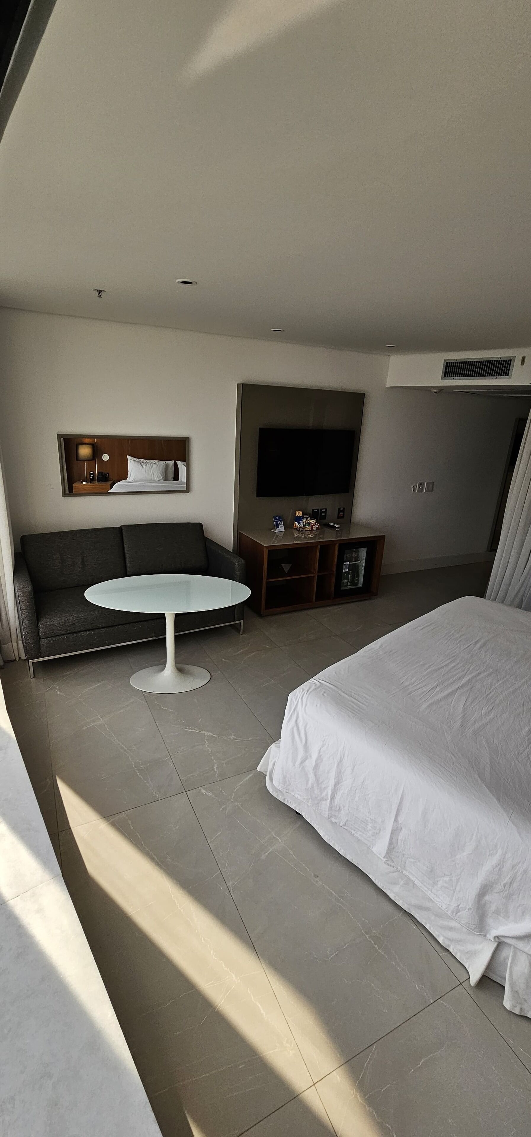 A hotel room with a bed, a sofa, a round table, a TV, and a small cabinet.