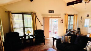 A cozy living room with a fireplace, a dining area, and a large window with curtains.