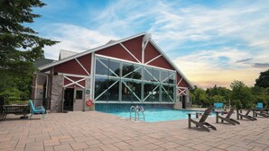 A poolside area with a large glass-enclosed pool, a red building with a white roof, and outdoor seating.
