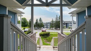 A covered porch with a view of a residential street and houses.