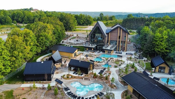 A resort with a large pool, multiple buildings, and a mountainous backdrop.