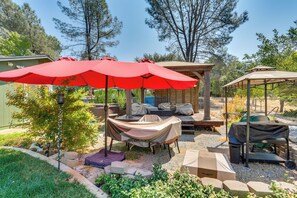 Un patio couvert avec des tables et des chaises, un barbecue et un kiosque.