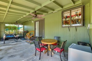 A covered patio with a round wooden table and chairs, a ceiling fan, and a window with colorful decorations. - Hot Tub, Dog-Friendly Yard! 3-Acre Redding Retreat (Redding)