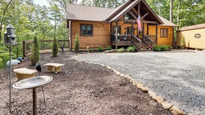 A wooden cabin with a porch, a flag, and a gravel driveway. - 'Next Stop Heaven' Game Room & Multiple Decks (Ellijay)