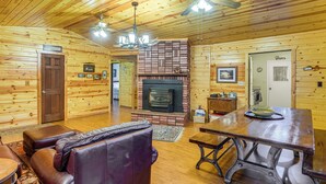 Ein gemütliches Blockhaus-Interieur mit Holzwänden, einem Kamin, Ledersitzmöbeln und einem Essbereich.