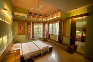 Un dormitorio con cama, escritorio, silla, ventilador de techo y ventana con cortinas.