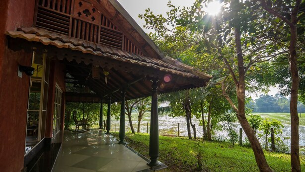 Un bâtiment en bois doté d’un porche carrelé qui donne sur un plan d’eau.