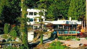 Ein modernes Haus mit Pool, umgeben von üppiger Vegetation.
