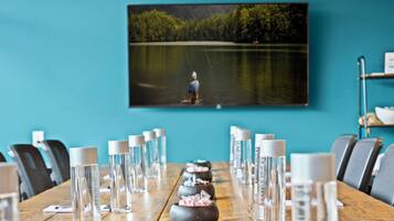 A conference room with a wooden table, water bottles, and a framed picture of a lake with a person fishing.