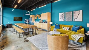 A modern interior with a teal wall, wooden furniture, a yellow sofa, and artwork. - The Speckled Trout Outpost (Damascus)
