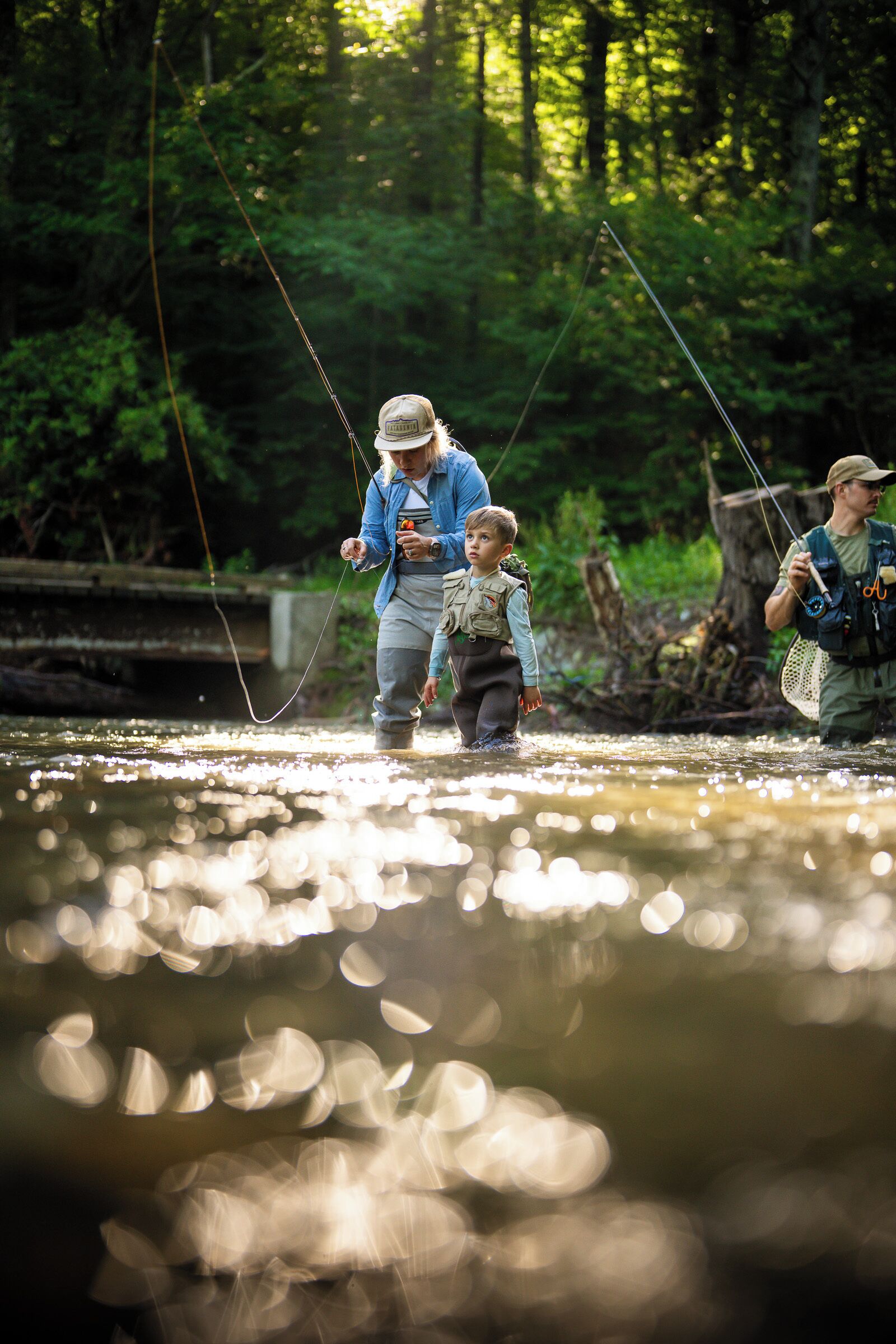 Une rivière où l’on peut voir des gens pêcher, entourée d’une forêt dense.