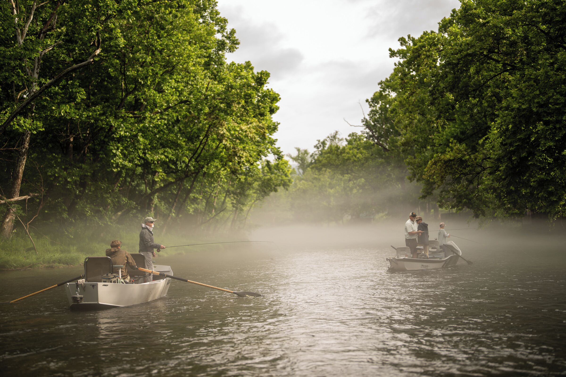 Two boats on a river surrounded by dense greenery.