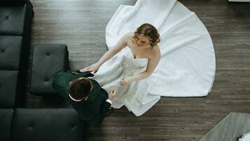 A top-down view of a room with a dark-colored sofa, a wooden floor, and a white dress.