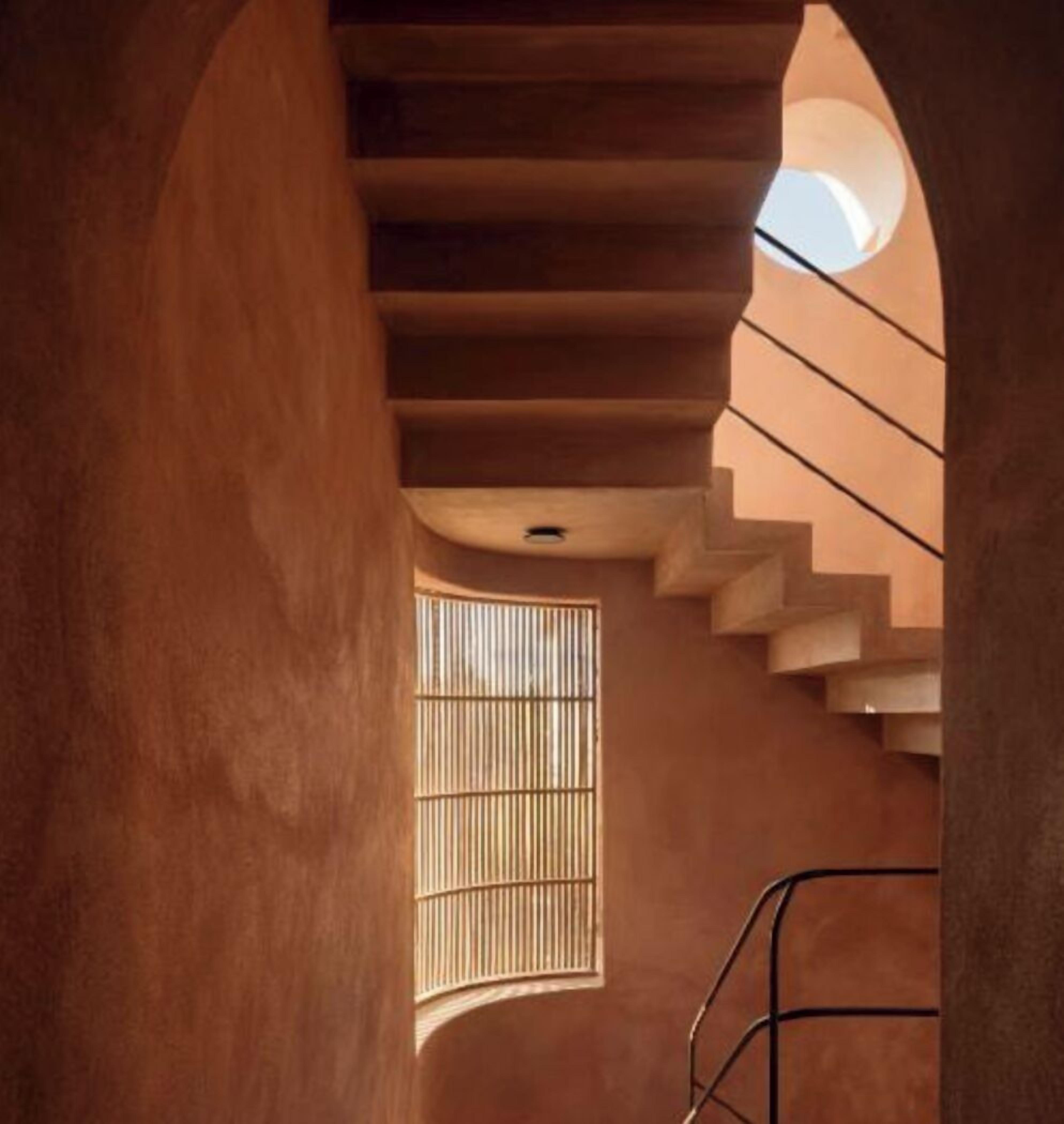 A staircase with a circular skylight and a window with vertical blinds.
