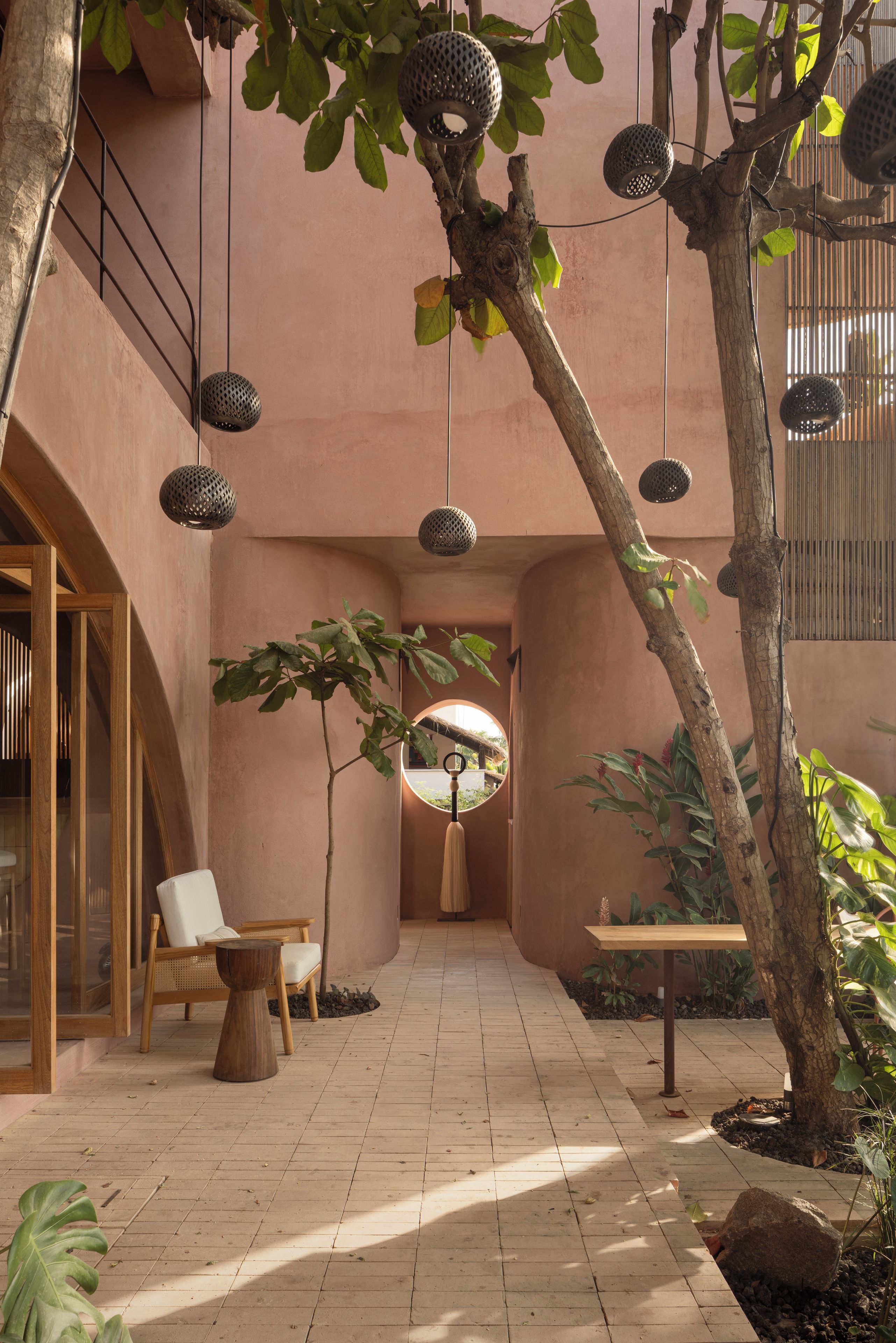 Un patio con área de descanso, luces colgantes y un árbol.