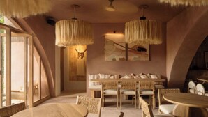 A cozy interior with a wooden dining table, a cushioned bench, and hanging light fixtures. - Hotel Boutique Xiqué (Brisas de Zicatela)