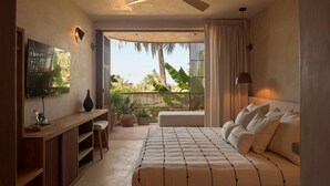 A bedroom with a bed, a desk, a chair, a TV, and a balcony with plants. - Hotel Boutique Xiqué (Brisas de Zicatela)