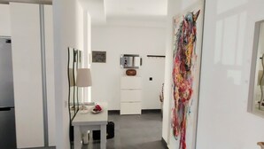 Una cocina moderna con armarios blancos, un refrigerador y un comedor con mesa y sillas.
