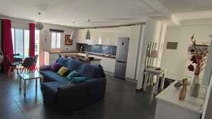 Una sala de estar moderna con sofá, mesa de comedor y zona de cocina.