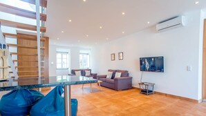 Een moderne woonkamer met een salontafel met glazen blad, een bank en twee loungestoelen.