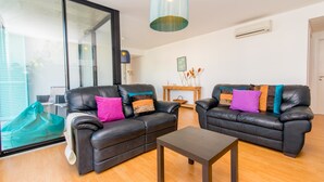 Ein modernes Wohnzimmer mit zwei schwarzen Ledersofas, einem Holztisch und einer blauen Pendelleuchte.