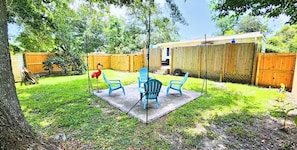 A backyard with a patio area, a wooden fence, and a tree. - Cozy Coastal Getaway – ½ Mile to Gulfport Beach (Gulfport)