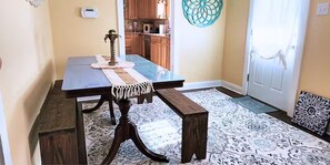 A dining area with a table, benches, and a patterned rug. - Cozy Coastal Getaway – ½ Mile to Gulfport Beach (Gulfport)