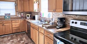 A kitchen with wooden cabinets, a granite countertop, a coffee maker, and a stove.