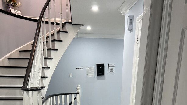 A staircase with white balusters and black handrails leading to a door with a black handle. - SH202-Cozy Holiday Home (Pickering)
