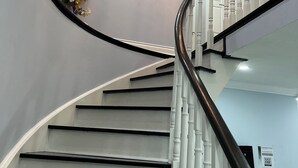 A staircase with white balusters, a black handrail, and a chandelier. - SH202-Cozy Holiday Home (Pickering)