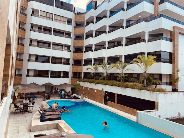 A modern hotel with a rooftop pool, outdoor seating, and multiple balconies. - Gold Flat by Apartamentos Jampa (João Pessoa)