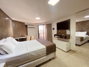 A hotel room with a bed, a desk, a TV, and a small seating area. - Gold Flat by Apartamentos Jampa (João Pessoa)