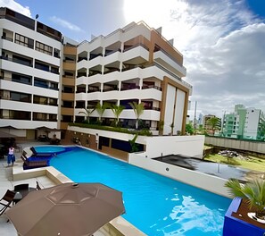 A modern hotel with a rooftop pool, multiple balconies, and a clear sky. - Gold Flat by Apartamentos Jampa (João Pessoa)